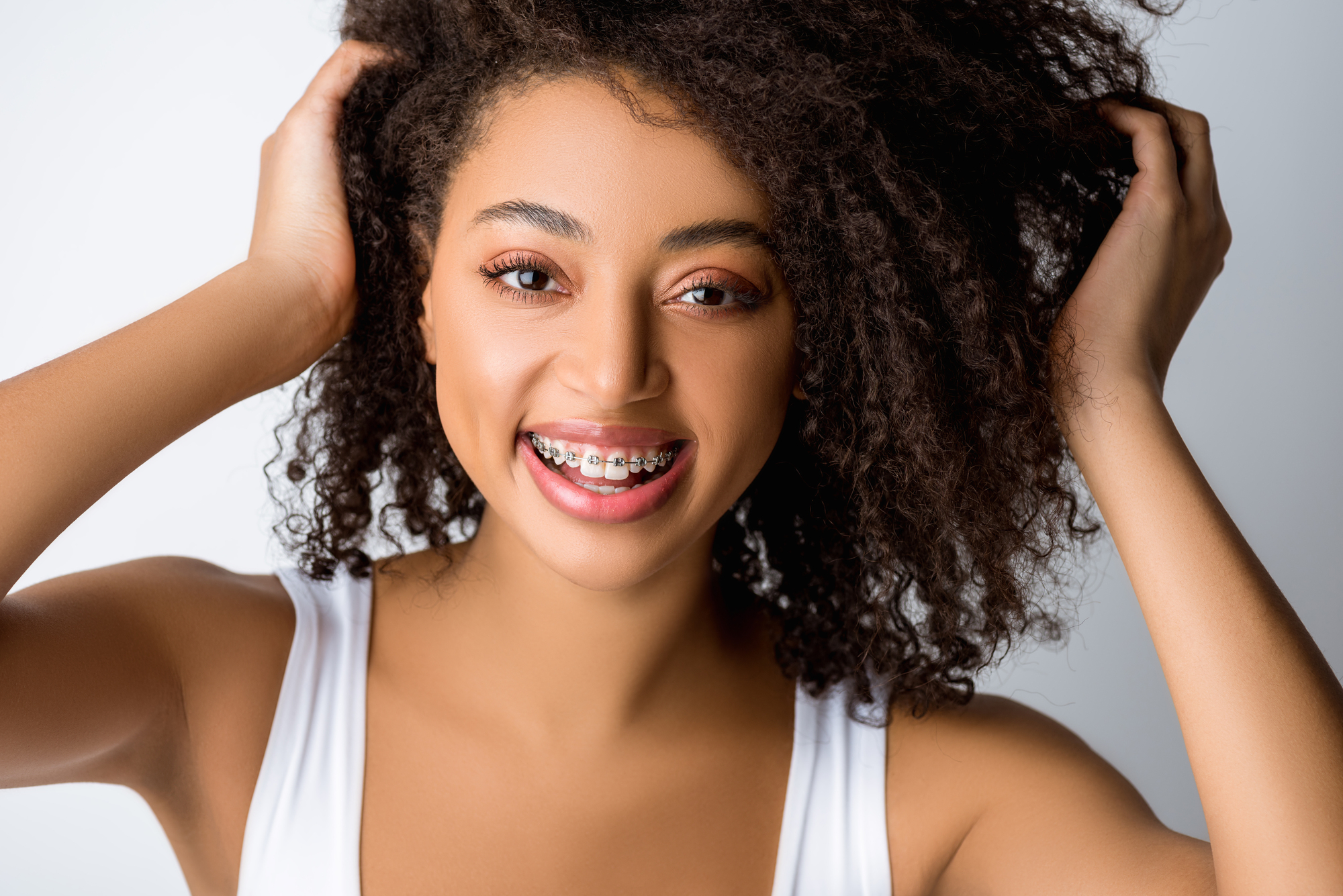 Smiling woman with transparent braces showcasing a confident and healthy smile, highlighting modern orthodontic solutions for straight teeth.