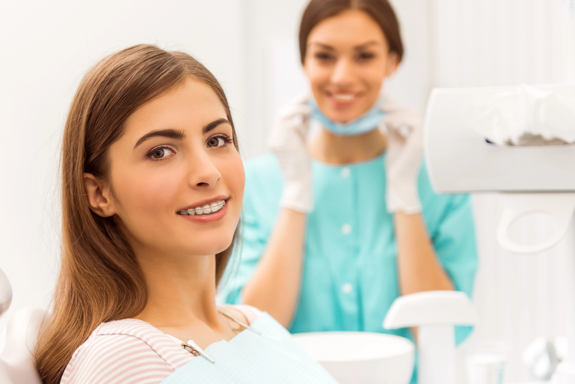 Young woman at the dentist's office with braces, receiving professional care for teeth whitening and straightening to achieve a perfect smile.